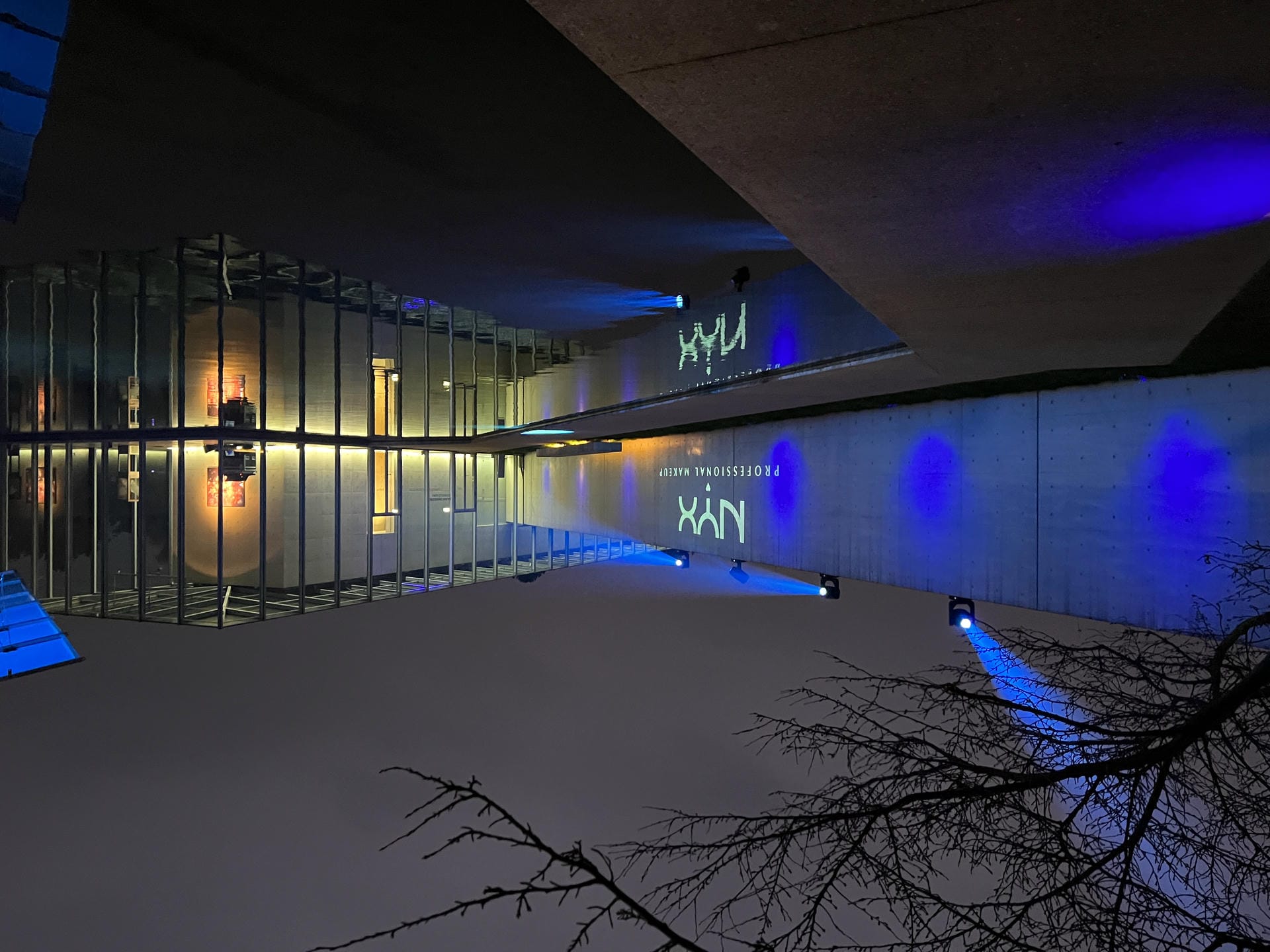 Nächtliche Außenfassade mit beleuchtetem Pool und projiziertem NYX Professional Makeup Logo im Rahmen der Brand Experience