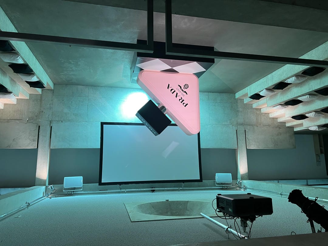 Prada Screening-Room mit gestufter Kissenbestuhlung und beleuchtetem Markenobjekt