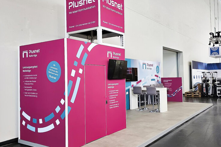 Messestand Plusnet mit Bildschirm und Barhockern