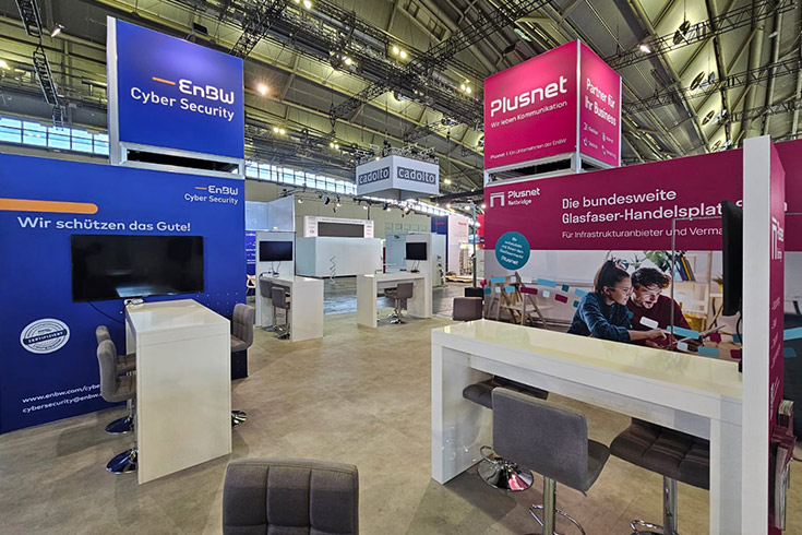 Messestand von EnBW Cyber Security und Plusnet mit Beratungsbereichen, Markenkommunikation und markanten Deckenelementen.
