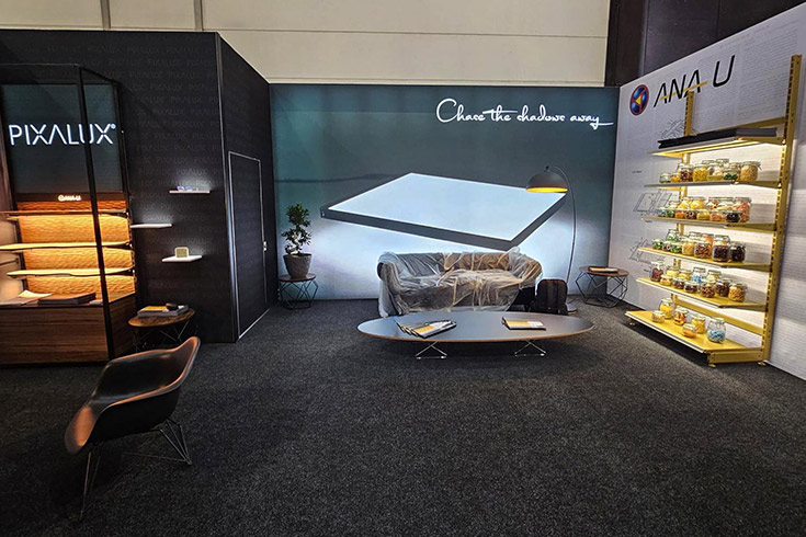 Hochwertiger Messestand mit beleuchteten Produktpräsentationen und gemütlichem Lounge-Bereich.